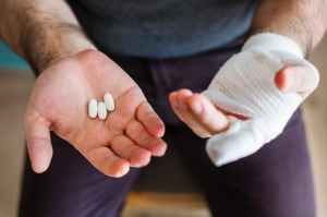 man holding three white medication pills
